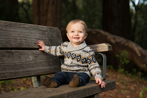 Happy one year old baby boy on bench