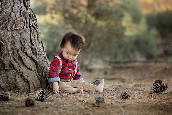 Baby boy outside surrounded by pine cones