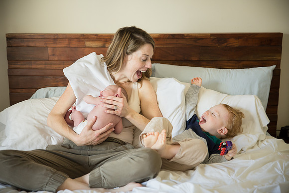 Mom laughs with son and newborn daughter on bed in Santa Monica