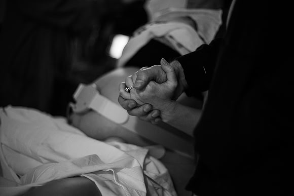 Pregnant woman squeezes husband's hand during contractions