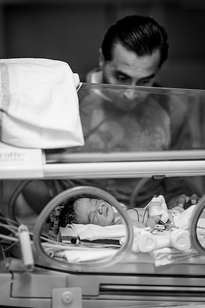 Father lovingly watches his newborn baby in the NICU